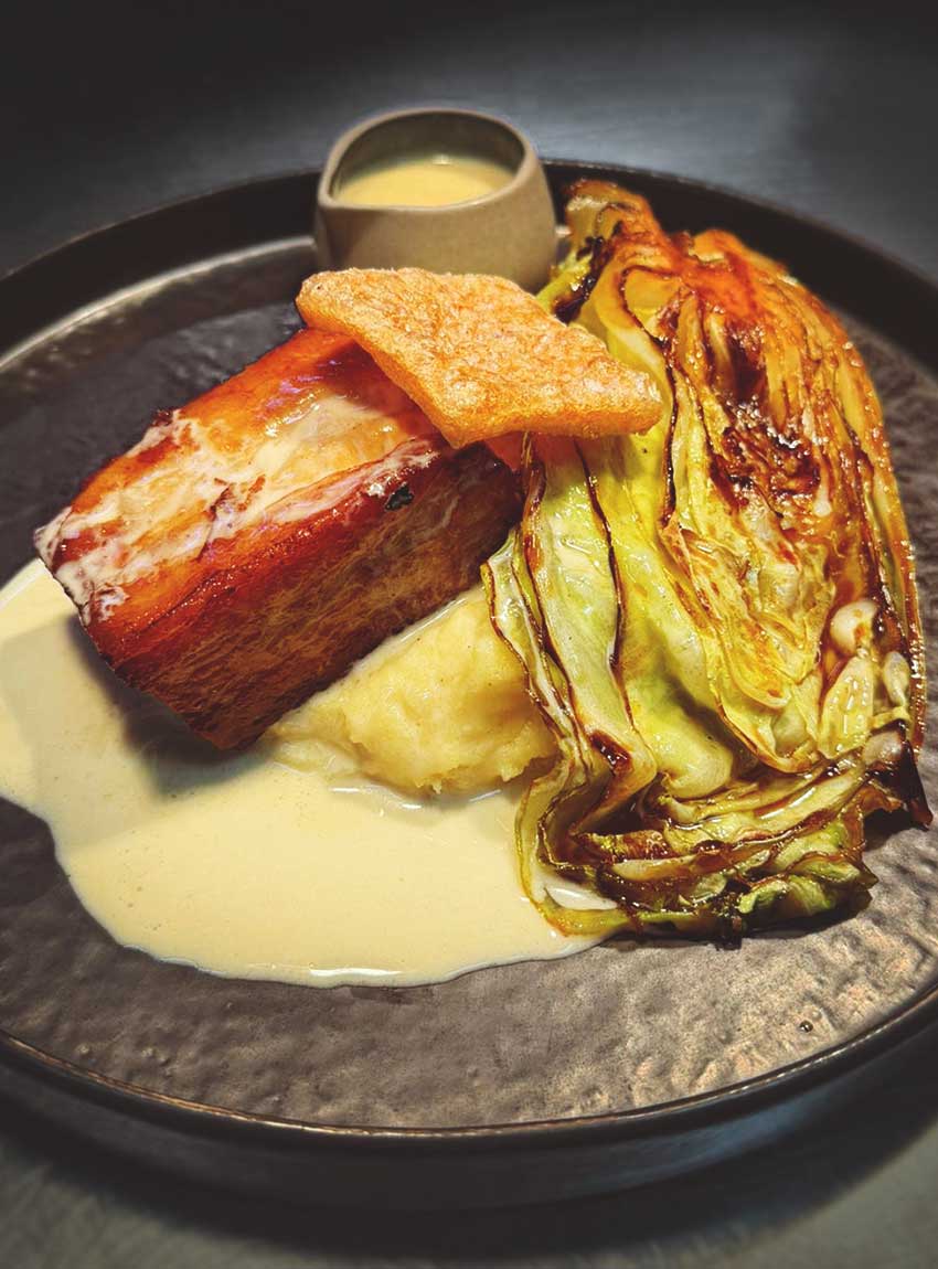 Slow cooked pork belly with Parmesan polenta, braised hispi cabbage and a Dijon mustard sauce.